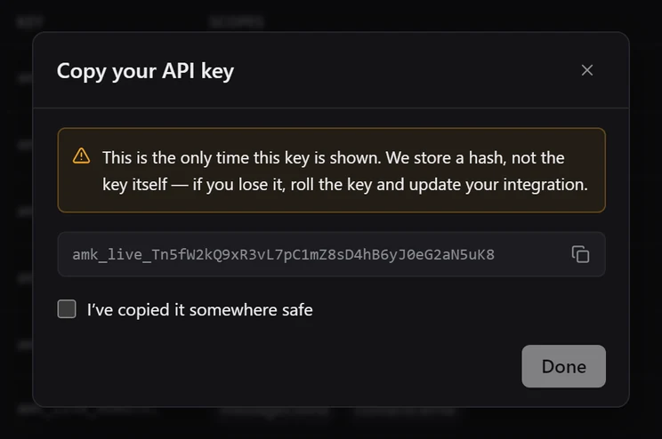 The Copy your API key dialog showing a full amk_live key, a warning that it is shown only once, and an unticked I've copied it somewhere safe checkbox with Done disabled