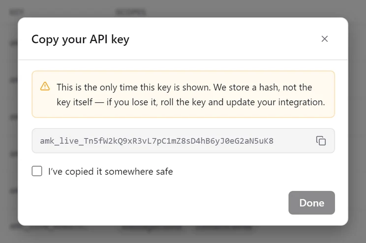 The Copy your API key dialog showing a full amk_live key, a warning that it is shown only once, and an unticked I've copied it somewhere safe checkbox with Done disabled